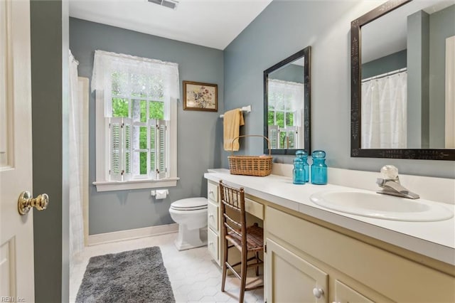 bathroom featuring toilet, vanity, curtained shower, and baseboards