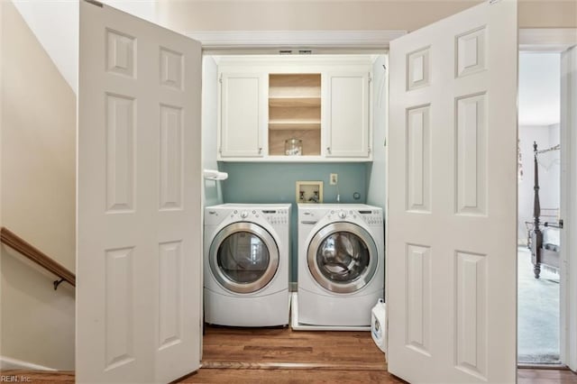 laundry room with cabinet space, washing machine and dryer, and wood finished floors