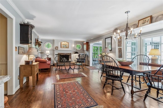 dining room featuring crown molding, wood finished floors, a fireplace with raised hearth, and a chandelier