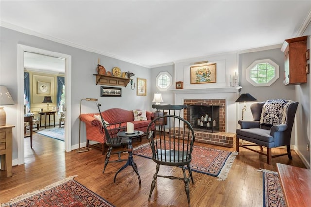 living room featuring ornamental molding, wood finished floors, a brick fireplace, and baseboards
