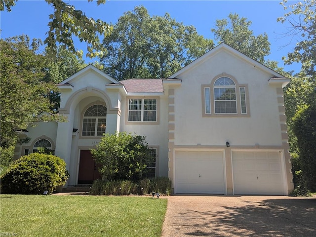 view of front of house with stucco siding, a garage, driveway, and a front lawn