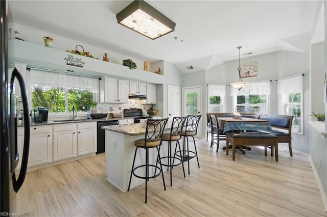 kitchen featuring black appliances, a sink, healthy amount of natural light, a kitchen breakfast bar, and lofted ceiling