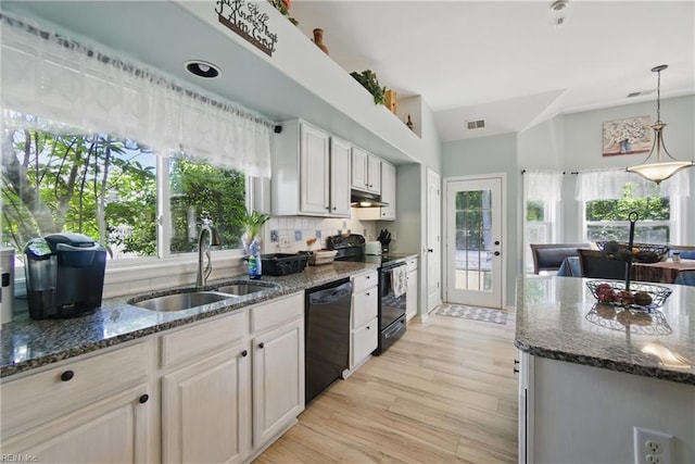 kitchen featuring black appliances, a sink, under cabinet range hood, and dark stone countertops
