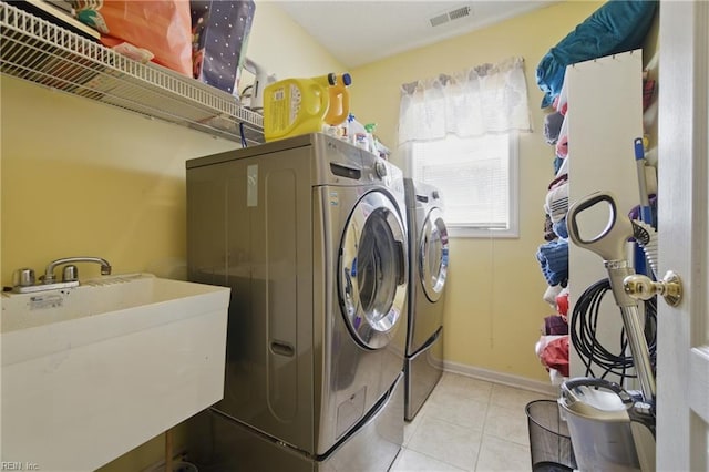 laundry room with washer and clothes dryer, light tile patterned flooring, and baseboards