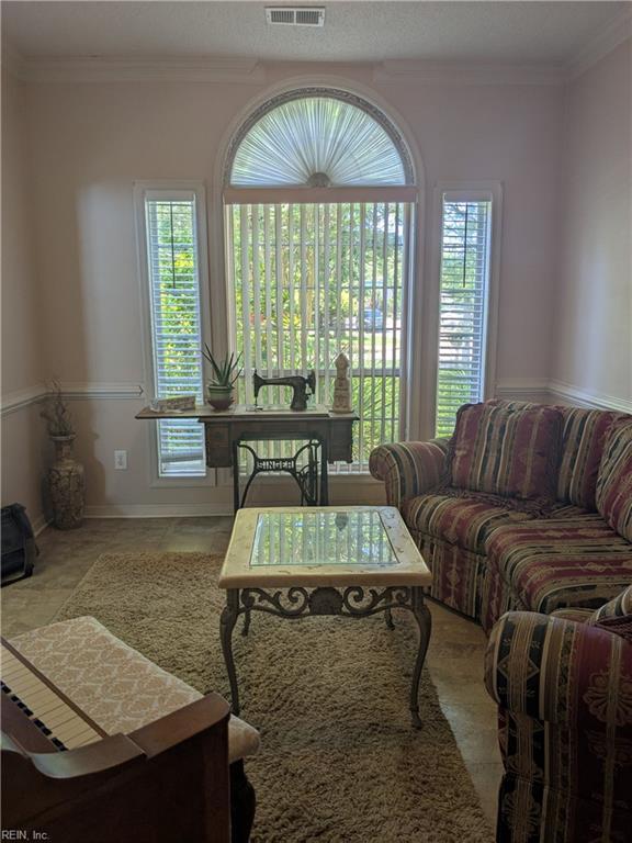 living room featuring healthy amount of natural light and crown molding
