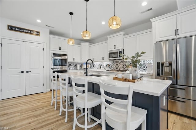 kitchen with stainless steel appliances, a sink, white cabinets, tasteful backsplash, and recessed lighting