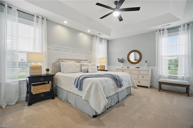 bedroom featuring light colored carpet, multiple windows, a decorative wall, wainscoting, and recessed lighting