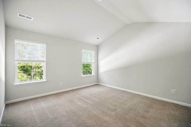 carpeted spare room with lofted ceiling, baseboards, and visible vents