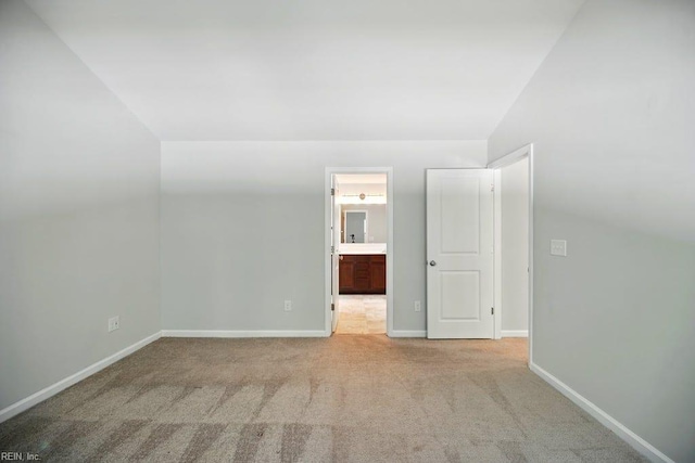 empty room with carpet flooring, baseboards, and lofted ceiling