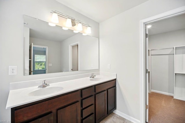 bathroom with double vanity, baseboards, and a sink