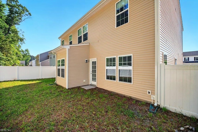 rear view of house with a lawn and a fenced backyard