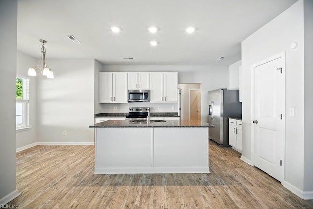 kitchen featuring light wood-style flooring, baseboards, dark stone counters, and appliances with stainless steel finishes