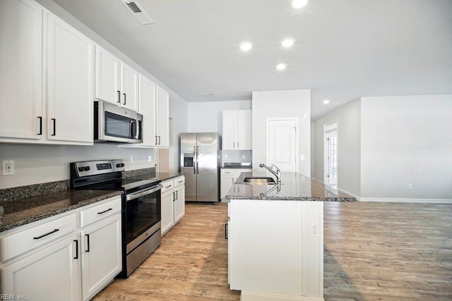 kitchen featuring recessed lighting, visible vents, light wood-style floors, stainless steel appliances, and a kitchen island with sink