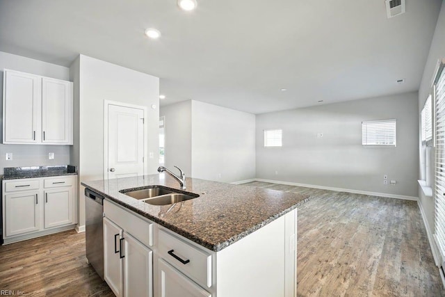 kitchen with a sink, dark stone countertops, visible vents, dishwasher, and light wood-style floors