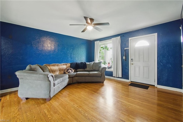 living room with light wood finished floors, baseboards, and a ceiling fan