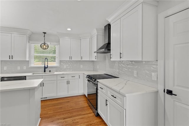 kitchen with wall chimney range hood, black range with electric stovetop, a sink, white cabinetry, and recessed lighting