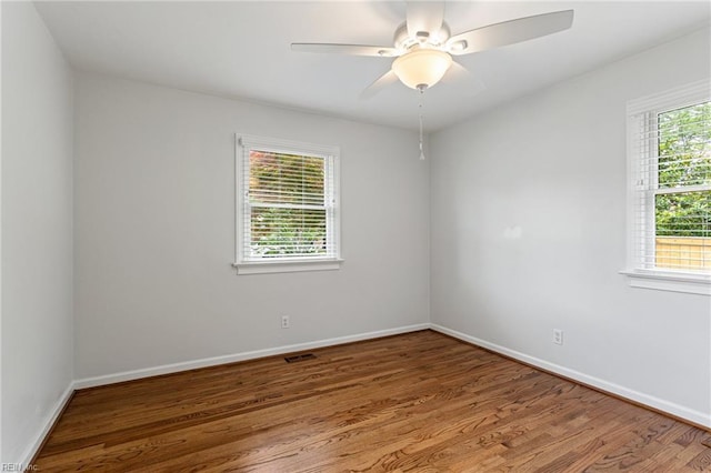 spare room featuring wood finished floors, baseboards, and a ceiling fan
