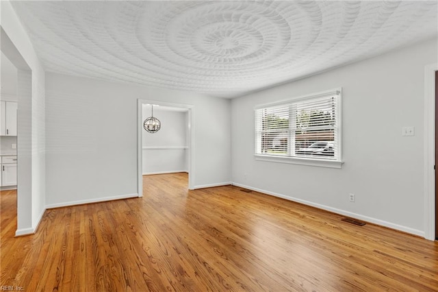 unfurnished living room with baseboards, light wood-style flooring, and a chandelier