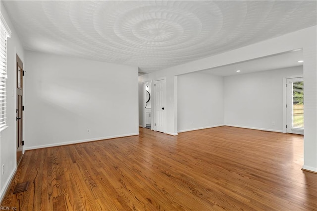 unfurnished living room with wood finished floors, baseboards, and recessed lighting