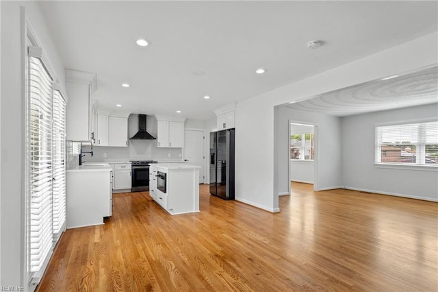kitchen with wall chimney range hood, refrigerator with ice dispenser, stainless steel electric stove, light countertops, and a center island