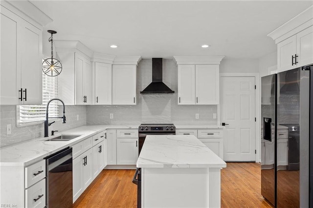 kitchen with wall chimney range hood, appliances with stainless steel finishes, a sink, a kitchen island, and white cabinetry