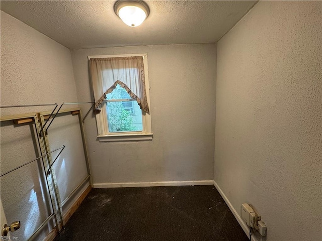 carpeted empty room featuring a textured ceiling, baseboards, and a textured wall