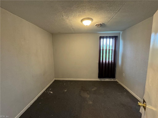 carpeted empty room featuring baseboards, visible vents, and a textured ceiling