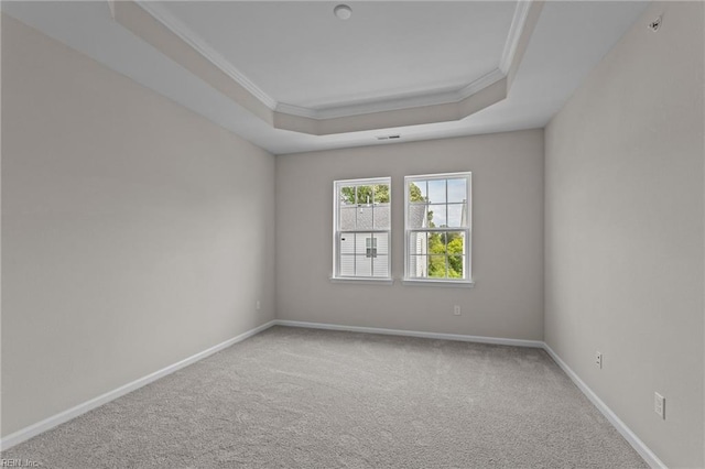 spare room featuring a tray ceiling, crown molding, carpet flooring, and baseboards