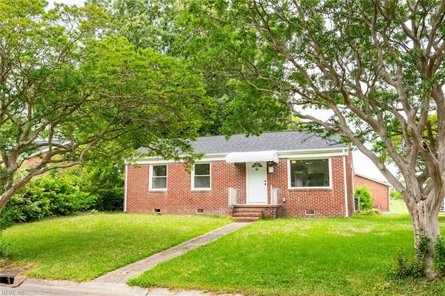 bungalow with roof with shingles, a front yard, brick siding, and crawl space