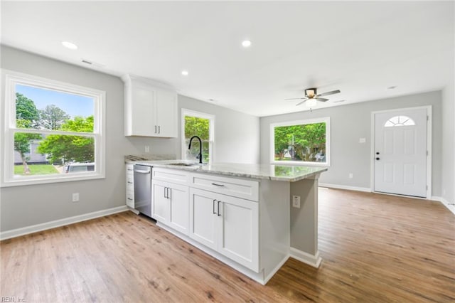 kitchen with a peninsula, light wood-type flooring, white cabinets, and a sink