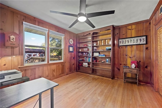 office space featuring light wood finished floors, wood walls, and ceiling fan