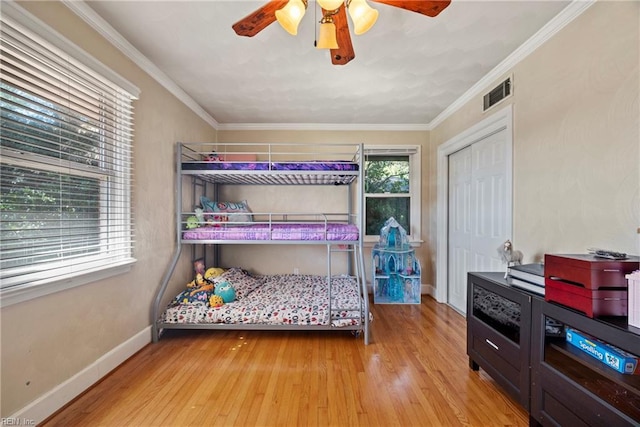 bedroom featuring wood finished floors, a closet, visible vents, baseboards, and ceiling fan