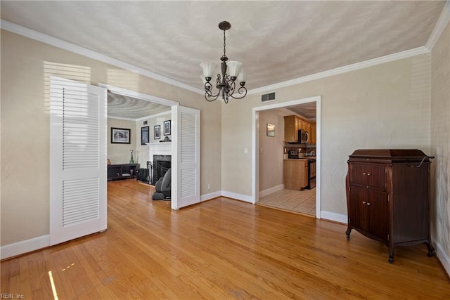 unfurnished dining area with an inviting chandelier, light wood-type flooring, visible vents, and a fireplace