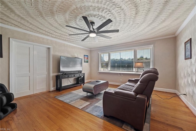 living area with ceiling fan, hardwood / wood-style flooring, baseboards, and ornamental molding