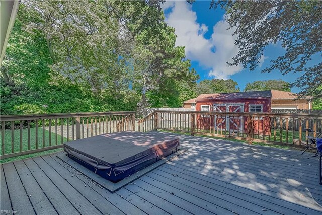 wooden terrace with an outdoor structure, fence, and a storage unit