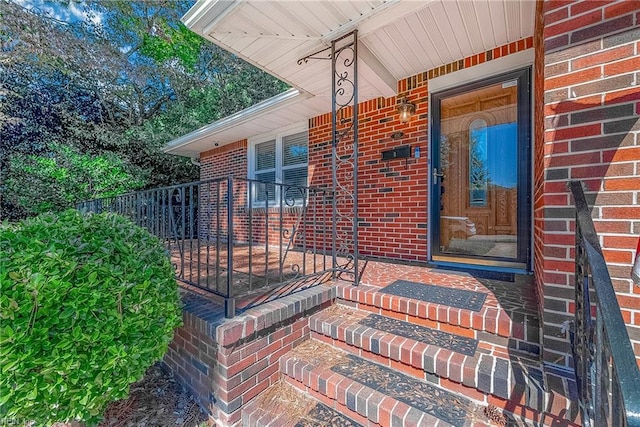 entrance to property with brick siding, covered porch, and fence