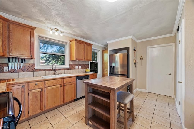 kitchen with ornamental molding, light tile patterned flooring, a sink, tasteful backsplash, and appliances with stainless steel finishes