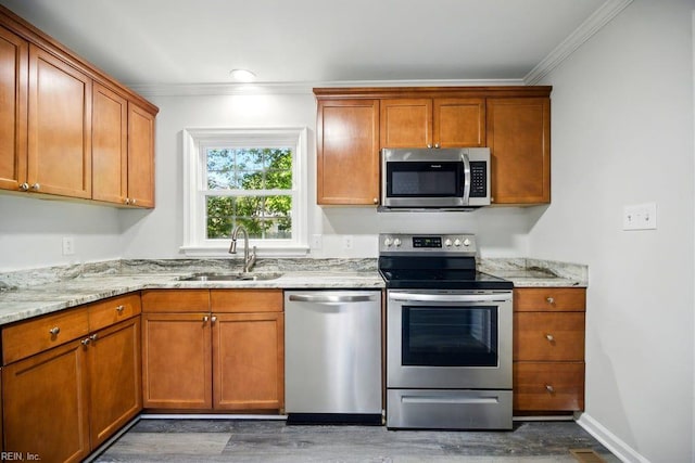 937 Sherry Cir, Newport News, VA 23608 - kitchen with brown cabinetry, a sink, crown molding, wood finished floors, and appliances with stainless steel finishes
