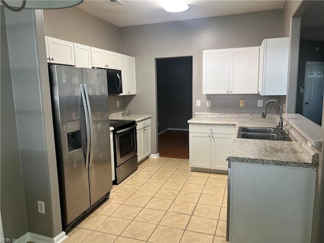 kitchen with stainless steel appliances, light tile patterned flooring, a sink, white cabinetry, and light countertops