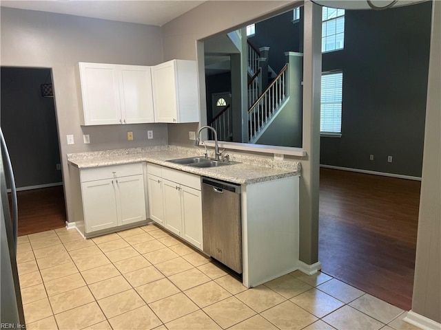 kitchen with light countertops, white cabinets, a sink, and dishwasher