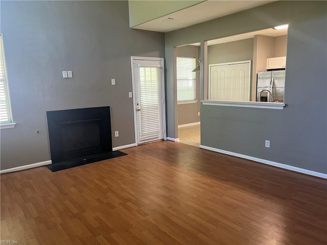 unfurnished living room featuring a fireplace, baseboards, and wood finished floors