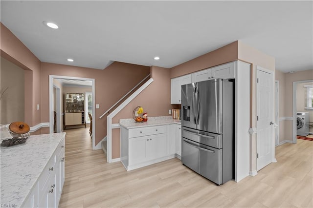 kitchen featuring stainless steel fridge with ice dispenser, washer / dryer, white cabinetry, light wood-type flooring, and recessed lighting