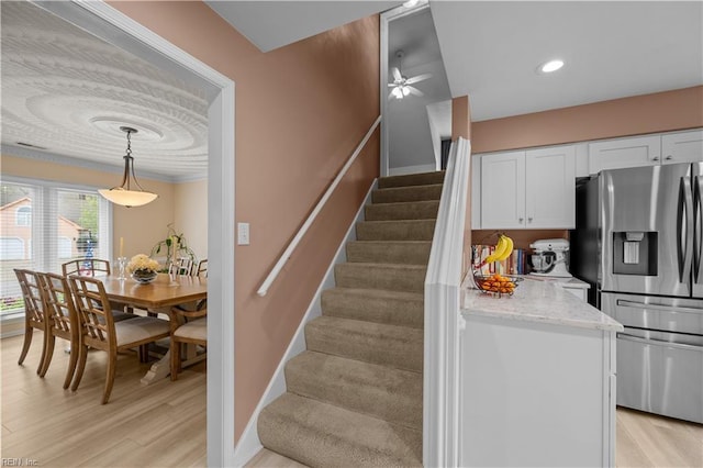 stairs featuring wood finished floors, a ceiling fan, and baseboards