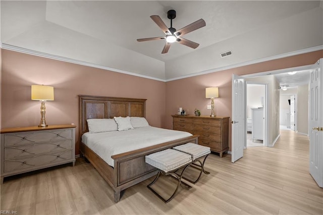 bedroom with light wood-style flooring, a ceiling fan, vaulted ceiling, and a raised ceiling