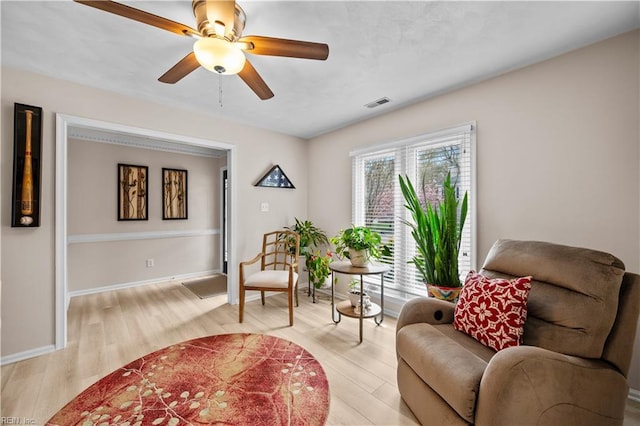 sitting room featuring ceiling fan, light wood-type flooring, and baseboards