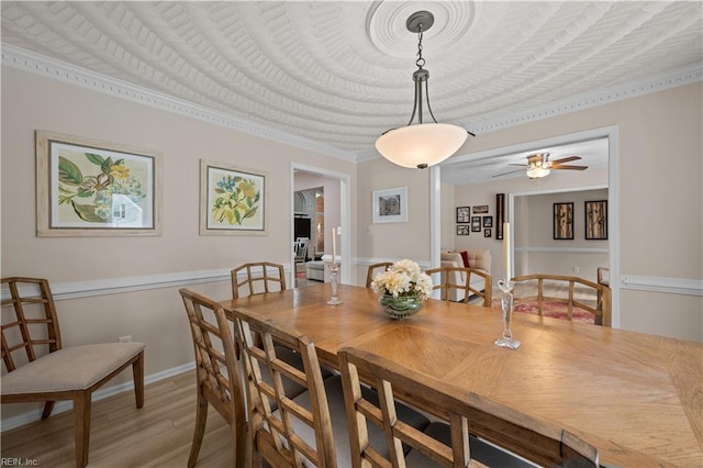 dining room with light wood finished floors, a ceiling fan, and crown molding