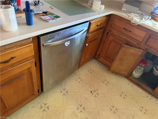 kitchen featuring dishwasher, brown cabinetry, light countertops, and light floors