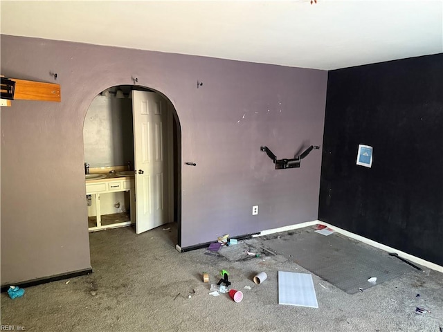 carpeted empty room featuring arched walkways and baseboards