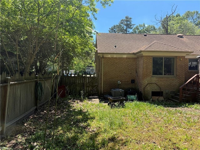 back of property with fence, a shingled roof, and brick siding