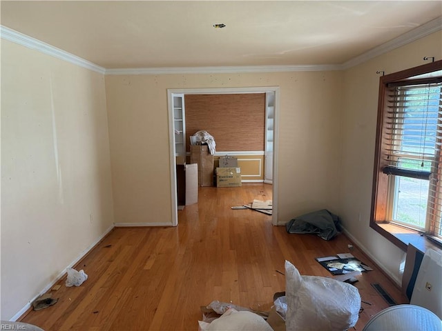 unfurnished room with plenty of natural light, crown molding, light wood-type flooring, and baseboards
